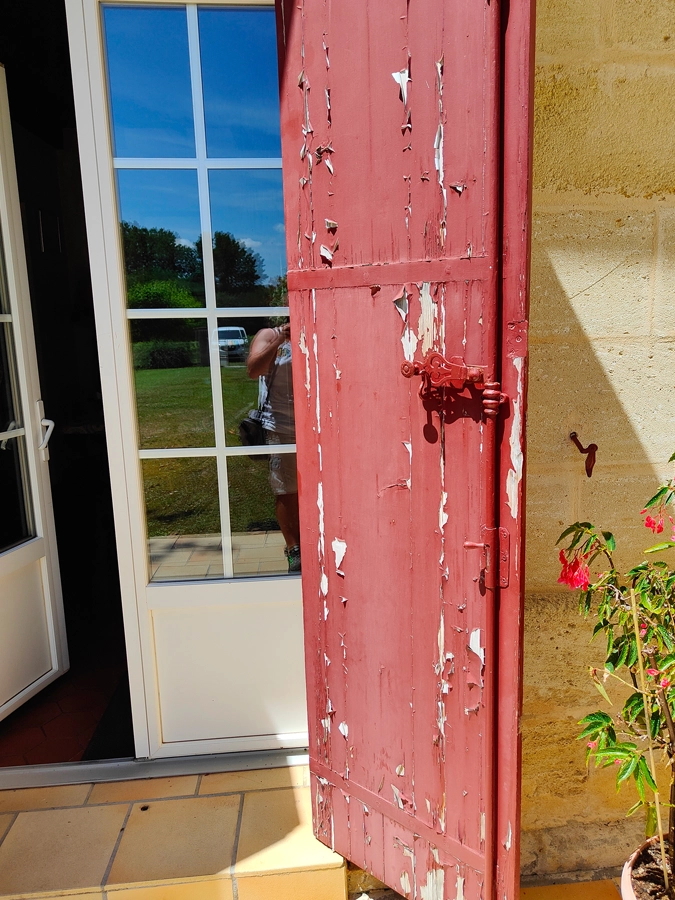 Volet rouge en mauvais état avec peinture écaillée - Le Peintre Aquitain